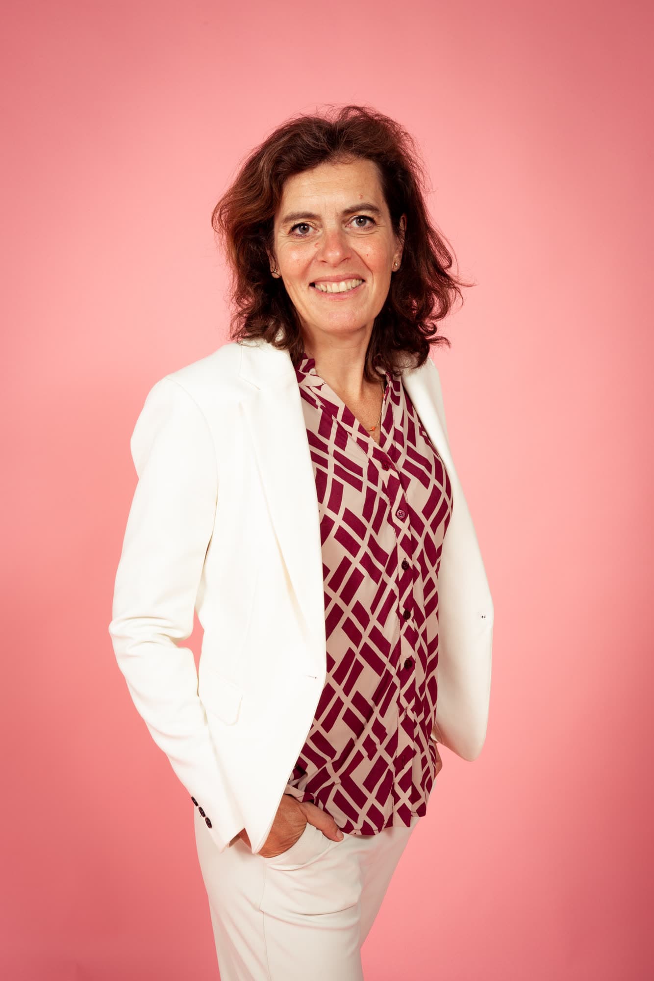 Emily Staphorst, ADHD-coach in Heemstede, staand tegen een roze achtergrond.